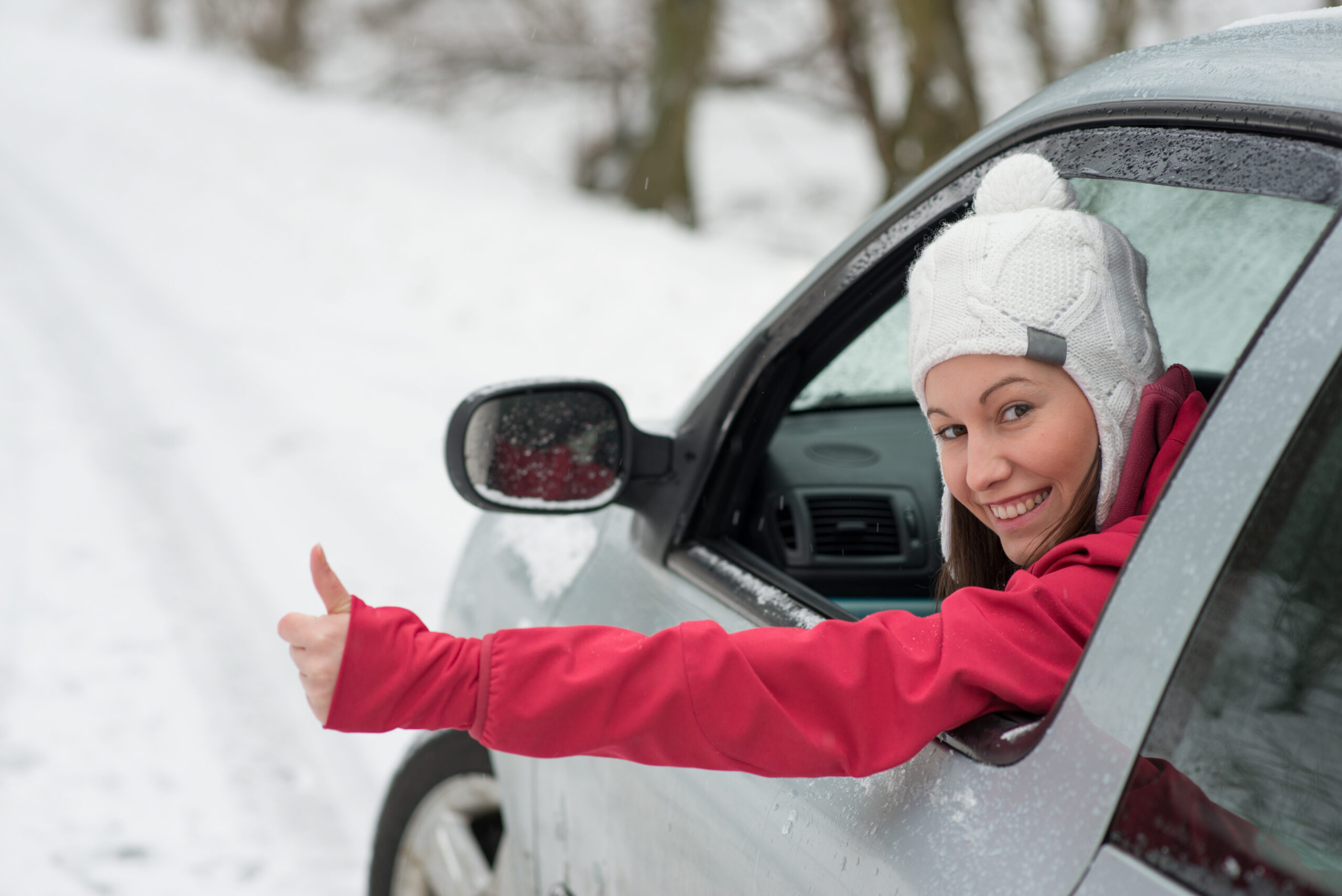 A woman looking outside her window giving a thumbs up